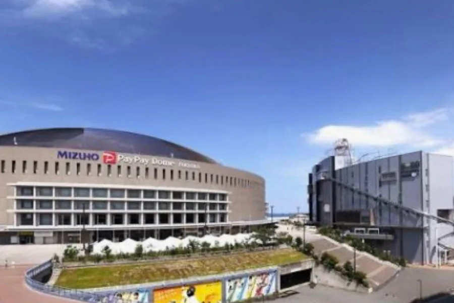 みずほPayPayドーム福岡の外観。ベージュの外壁と銀色のドーム屋根の建物に「MIZUHO PayPay Dome FUKUOKA」の看板が掲げられ、右手に隣接する建物が並んでいる