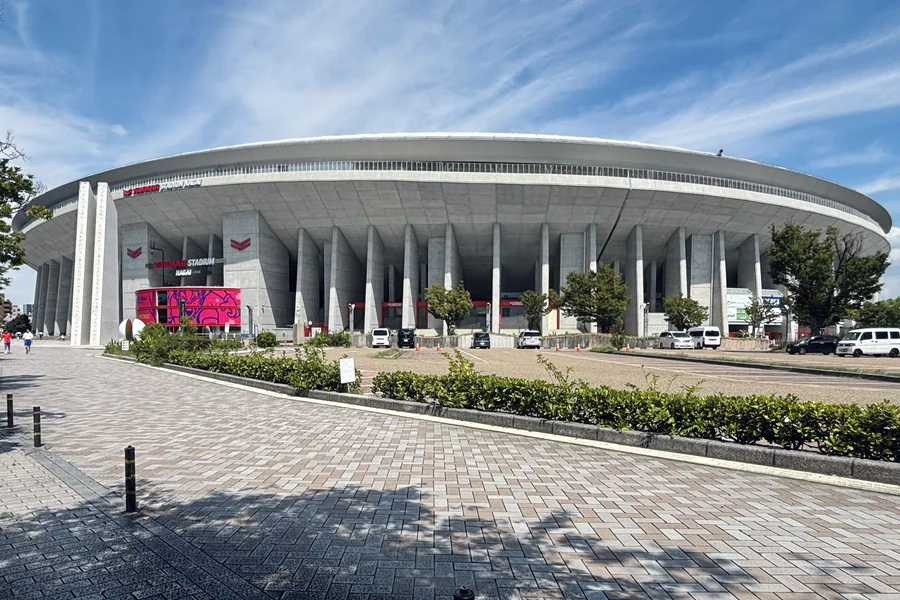 ヤンマースタジアム長居の外観。白い庇が大きく張り出した楕円形のスタジアムで、低層部にコンクリートの柱が並び、赤い館名の看板が出ている